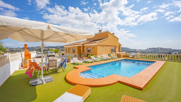A rooftop pool with a curved edge, surrounded by lounge chairs and umbrellas, and a view of the landscape in the background. - Villa Pastor - Plusholidays (Calpe)