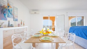 A dining area with a wooden table set for six, surrounded by white chairs. - Villa Pastor - Plusholidays (Calpe)