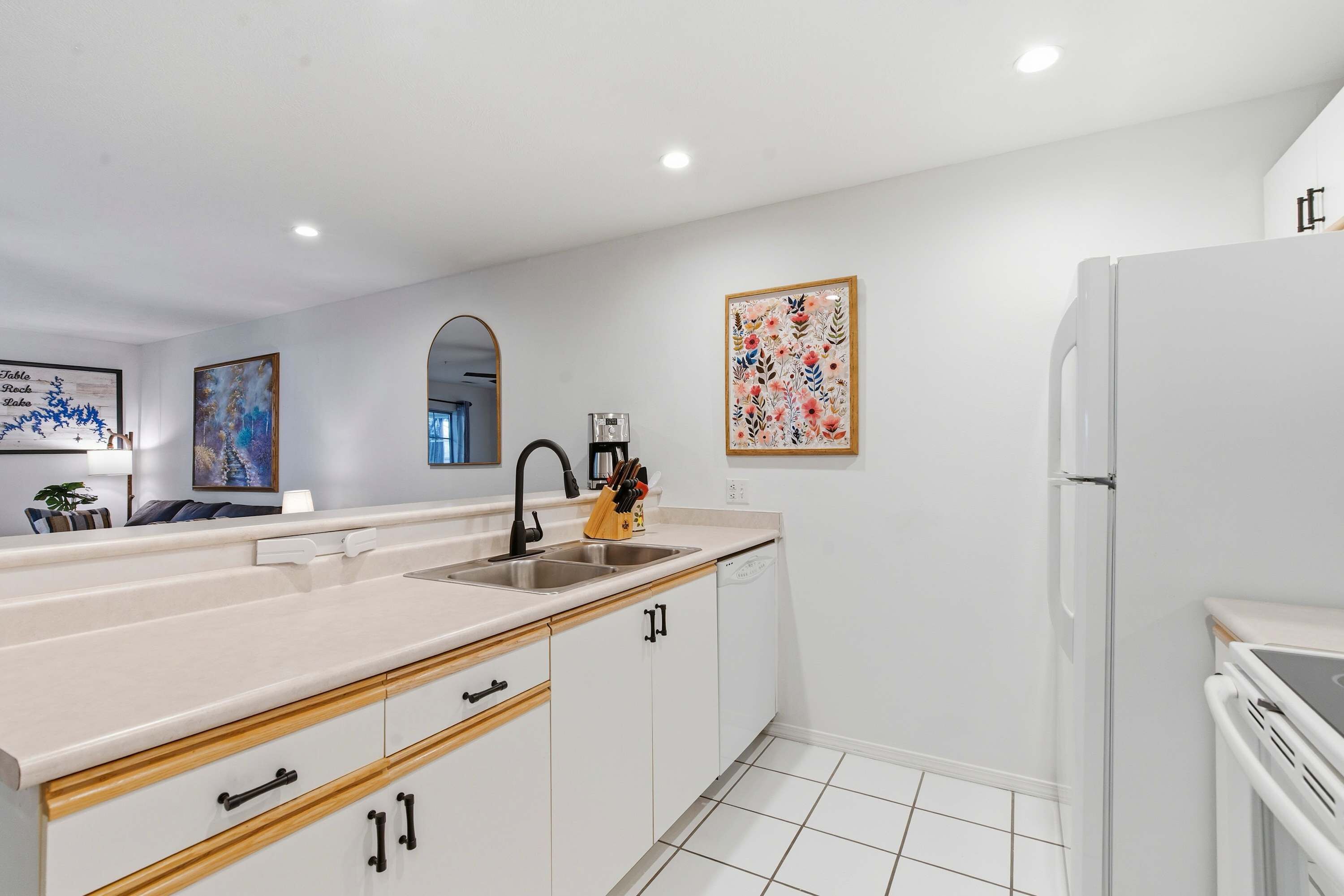 A modern kitchen with white cabinetry, a double sink, and a refrigerator.
