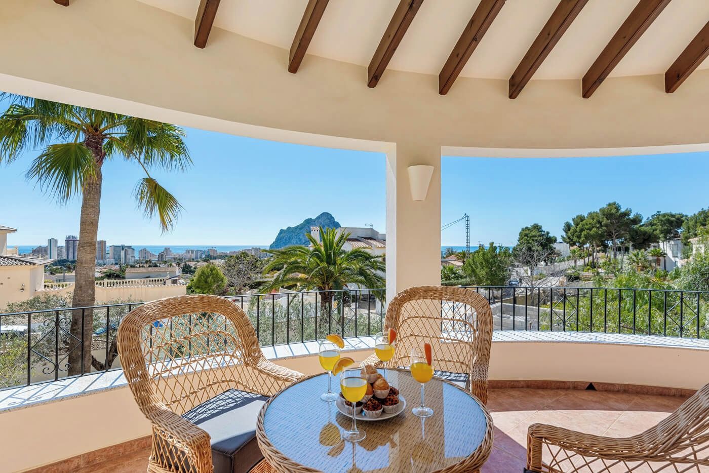 A balcony with wicker furniture, a round table, and a glass of orange juice.
