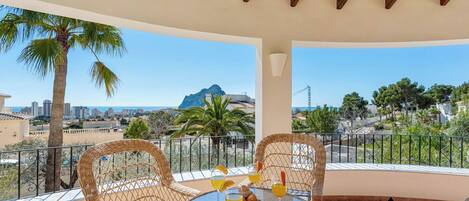 A balcony with wicker furniture, a round table, and a glass of orange juice.