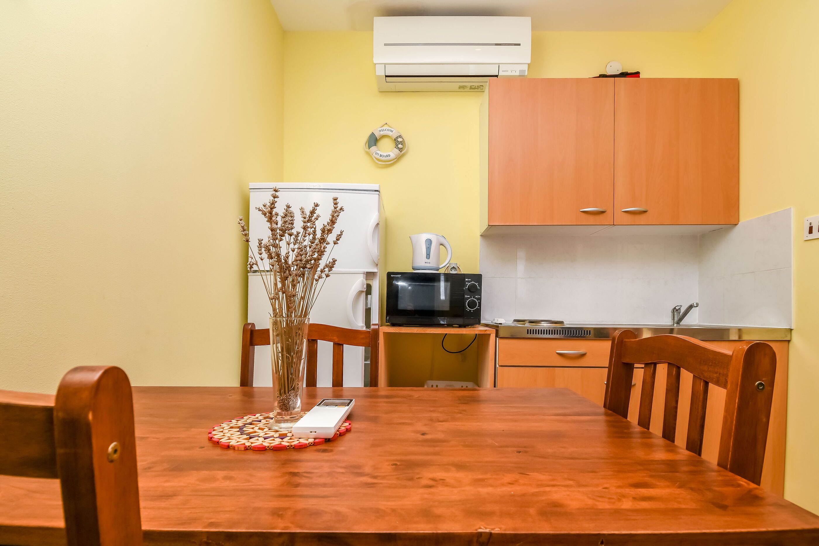 Une cuisine de taille réduite, avec une table en bois, des chaises, un réfrigérateur, un four à micro-ondes et un évier.
