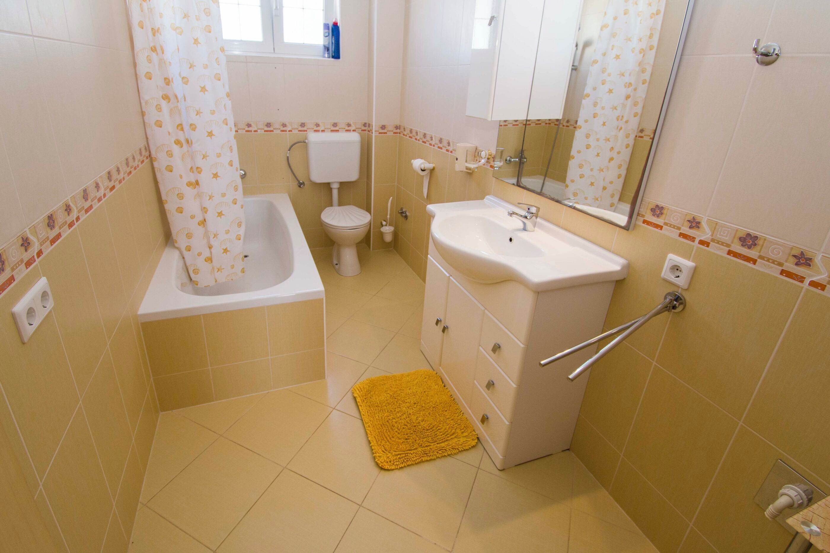 A bathroom with a bathtub, toilet, sink, and mirror.