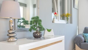 A white dresser with a lamp, a bonsai tree, and a vase with flowers. - Villa Manolet - plusholidays (Calpe)