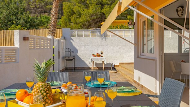 An outdoor dining area with a table set for breakfast, including fruits, pastries, and drinks. - Villa Manolet - plusholidays (Calpe)