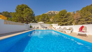 A swimming pool with lounge chairs and a mountain backdrop. - Villa Manolet - plusholidays (Calpe)