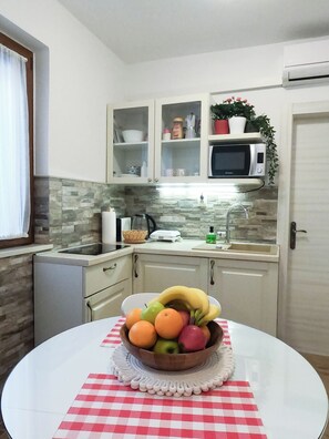 Una cocina con microondas, armarios y un frutero sobre una mesa.