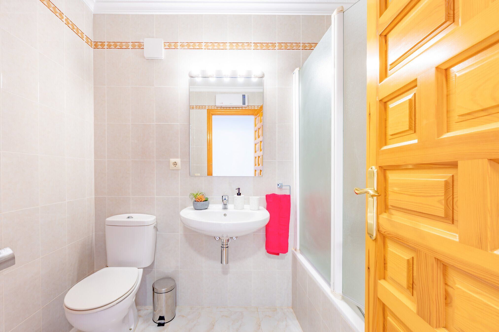 A bathroom with a toilet, sink, and mirror.