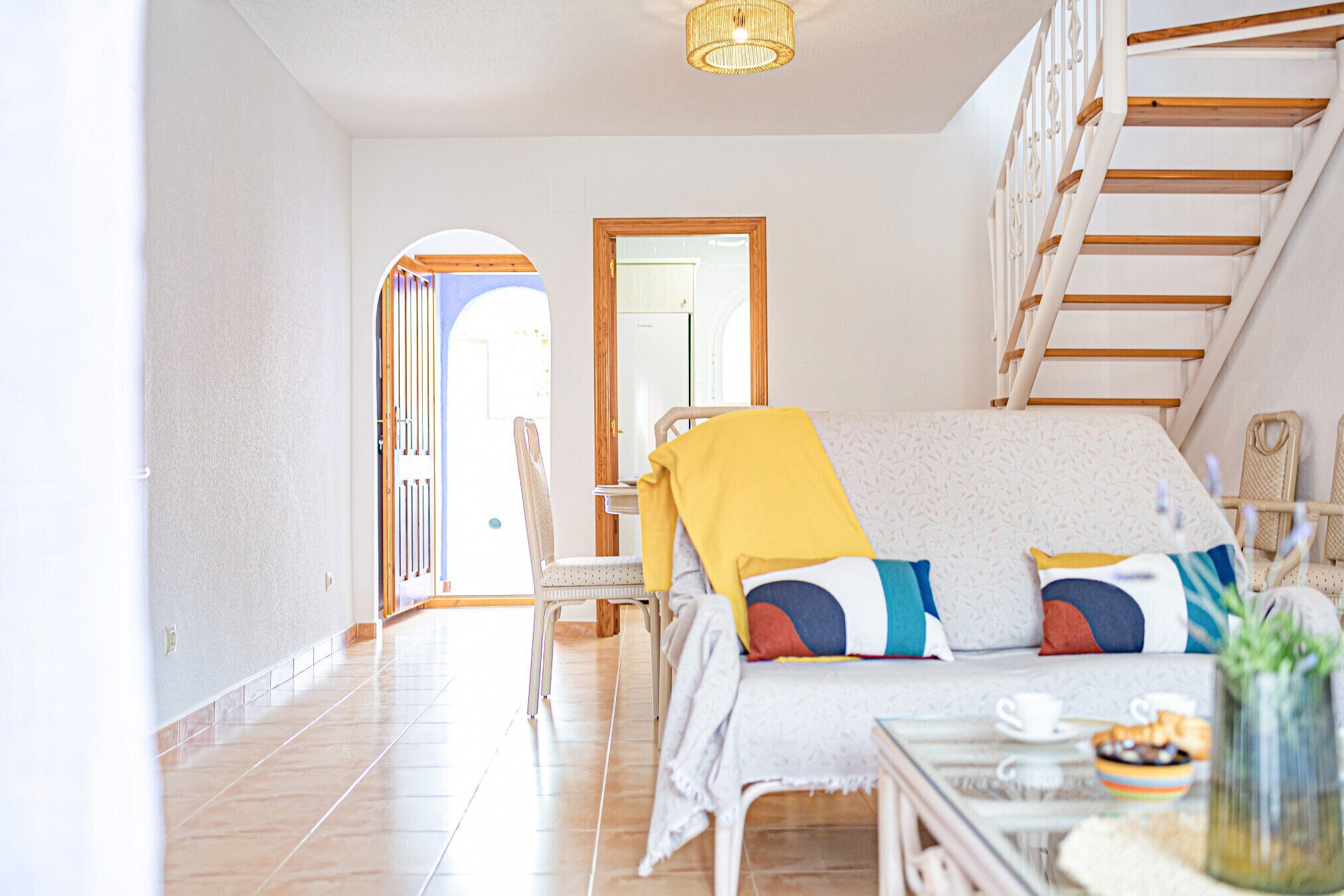 A bright room with a sofa, a coffee table, and a staircase.