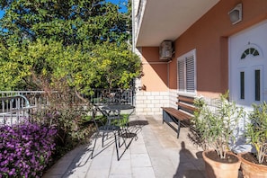 Eine Terrasse mit Gartenmöbeln, einer Bank und Topfpflanzen.