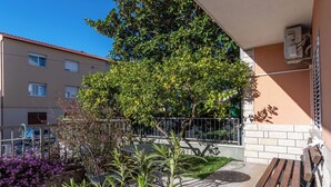 Un balcon avec un banc en bois, un pot de fleurs et une vue sur un immeuble dont le toit est recouvert de tuiles.