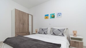 Une chambre à coucher comprenant un lit, une armoire, une table de chevet et deux œuvres d’art murales.