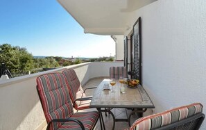 Un balcone con un tavolo, due sedie a righe e vista sul paesaggio.