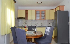 A compact kitchen with a dining table and chairs, a refrigerator, and a window with curtains. - House DD With Heated Pool (Okrug)