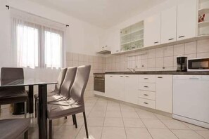 Una cucina moderna con mobili bianchi, un tavolo da pranzo con sedie e un forno a microonde.