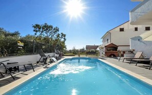 A swimming pool with lounge chairs and a barbecue area, surrounded by buildings and trees. - House DD With Heated Pool (Okrug)
