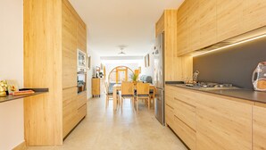 Une cuisine moderne avec des meubles en bois, un îlot central et un coin repas comprenant des chaises et une table.