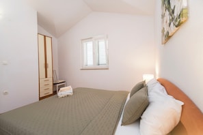 Un dormitorio con cama, mesita de noche, ventana y puerta.