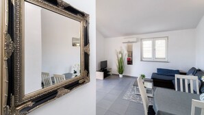 A living room with a dining area, a large ornate mirror, a sofa, a TV, and a potted plant. - Apartment Massimo Brooklyn (Tribunj)