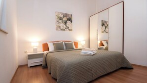 A modern bedroom with a large bed, two bedside tables with lamps, a large mirror, and artwork on the wall. - Apartment Massimo Brooklyn (Tribunj)