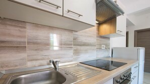 Een moderne keuken met een roestvrijstalen spoelbak, een inbouwoven en een houten aanrecht.