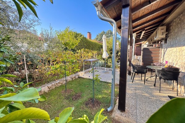 A garden with a patio area featuring outdoor furniture and a stone wall. - Apartments Matosic (Omisalj)