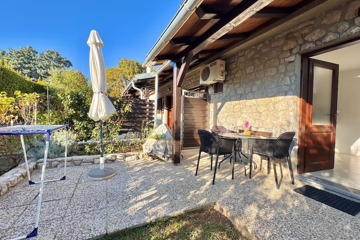 A patio with a table and chairs, an umbrella, and a stone wall.