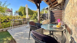 An outdoor patio with a round table, two chairs, and a small table with a drink. - Apartments Matosic (Omisalj)