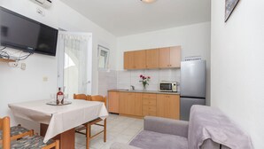 A compact living space with a dining area, kitchenette, and a gray sofa. - Apartments Pejo (Vodice)