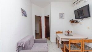 A small, clean room with a sofa, a table, and a TV mounted on the wall. - Apartments Pejo (Vodice)