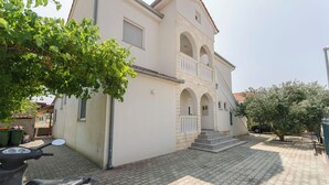 A building with a white facade, stone accents, and a balcony. - Apartments Pejo (Vodice)