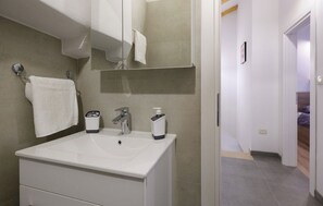 A modern bathroom with a white sink, a mirror, and a towel rack. - House Casa Della Nonna (Krsan)