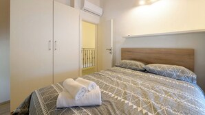 A bedroom with a bed, pillows, a wardrobe, and an air conditioning unit. - House Casa Della Nonna (Krsan)