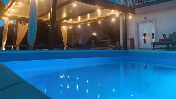 Un espace piscine comprenant un patio couvert, une piscine et un bâtiment doté d’un balcon.