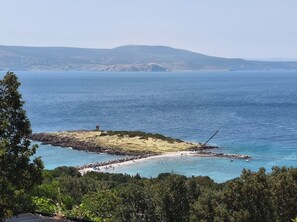 A coastal landscape with a beach, rocky outcrops, and a lighthouse in the distance. - Villa My day House (Novi Vinodolski)