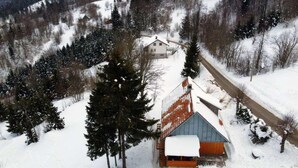 Paesaggio innevato con una baita di legno e una strada.