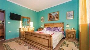 Une chambre à coucher avec un lit en bois, une commode, une table de chevet et un téléviseur.