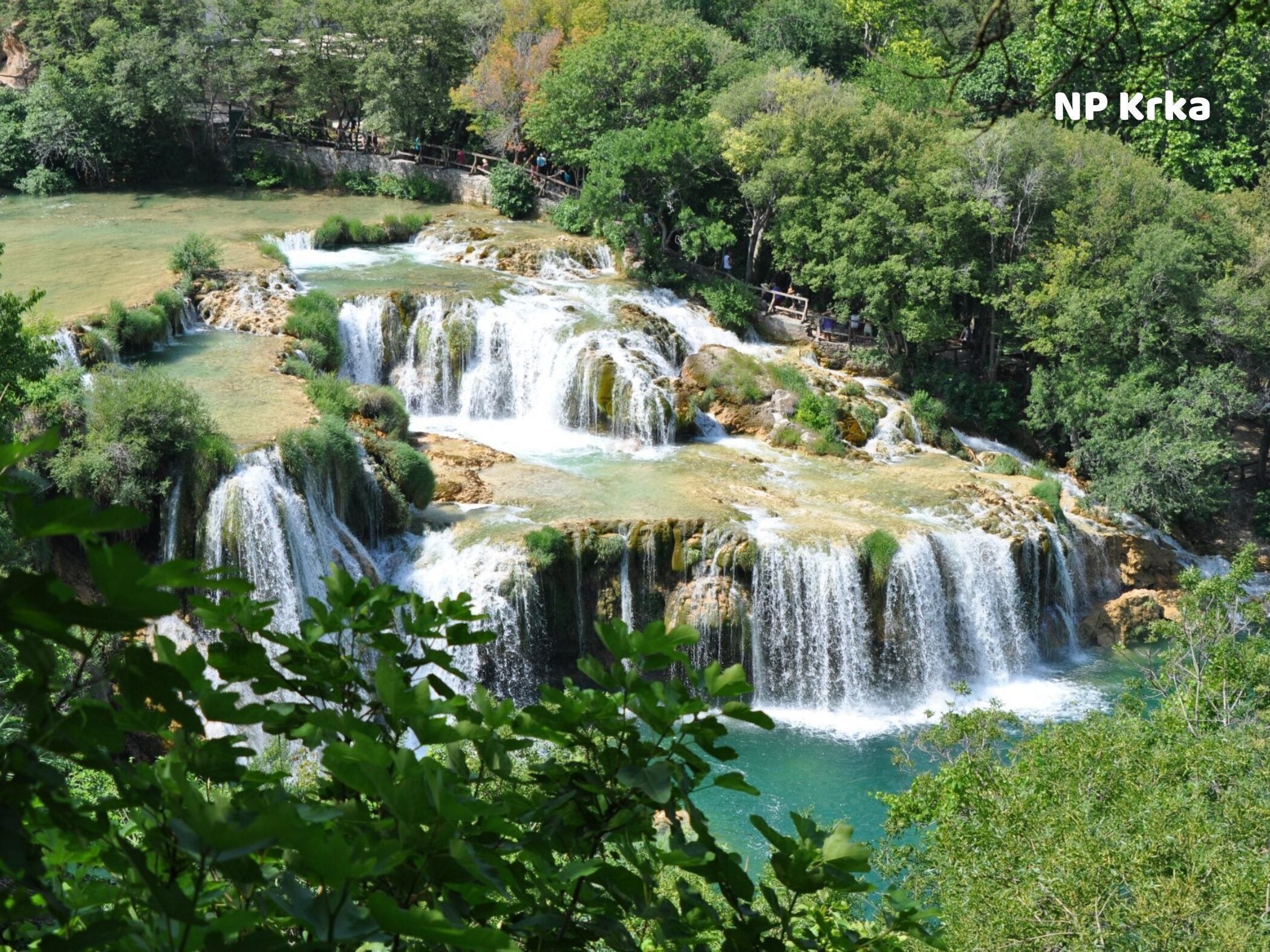A waterfall with multiple cascades surrounded by lush greenery.