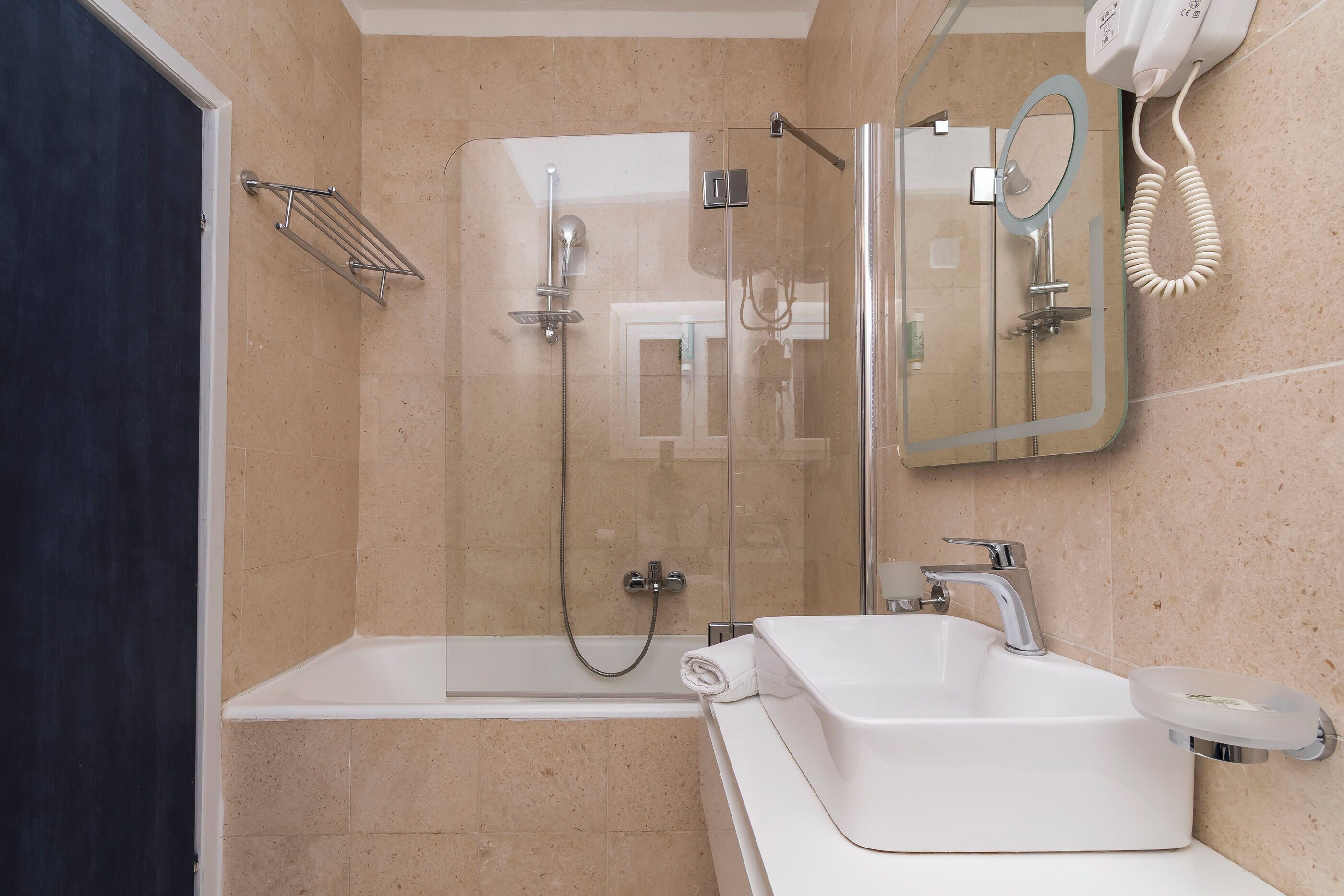 A modern bathroom with a glass-enclosed shower, a white bathtub, and a sink with a mirror.