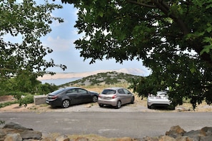 Three cars parked on a gravel road with a mountainous backdrop and a body of water. - House Velebit by the sea (Senj)