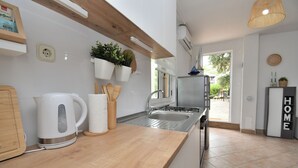 A modern kitchen with a wooden countertop, stainless steel appliances, and a view of the outdoors. - House Velebit by the sea (Senj)
