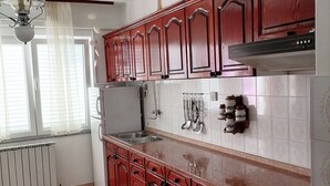 A kitchen with wooden cabinets, a stainless steel sink, and a black oven. - Apartments Poldan (Rab)