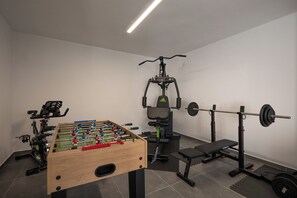 Un gimnasio con mesa de fútbol de mesa, equipamiento de levantamiento de pesas y máquinas de ejercicio.
