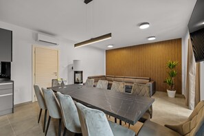 Un comedor moderno con una mesa de mármol, sillas con cojines, un sofá y una planta en maceta.