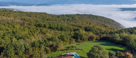 A modern house with a swimming pool, surrounded by lush greenery and hills.