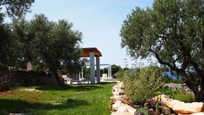 Ein Garten mit einer Pergola, einer Steinmauer und einer Sitzgelegenheit im Freien.