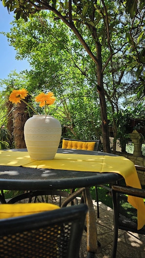 An outdoor dining area with a table covered by a yellow tablecloth, surrounded by chairs with yellow cushions. - Apartments Seagreen Villas (Novi Vinodolski)