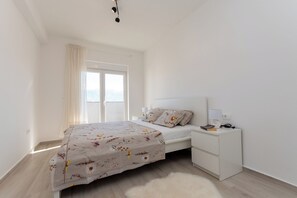 A bedroom with a bed, bedside table, and a window. - Apartment Sankovic (Rovinj)