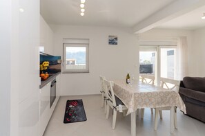 A dining area with a table, chairs, and a view through a window. - Apartment Sankovic (Rovinj)