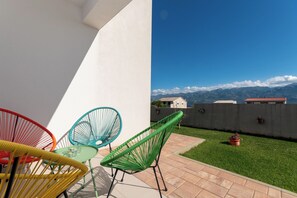A patio with chairs and a table, a small lawn, and a view of mountains. - Apartment Sankovic (Rovinj)